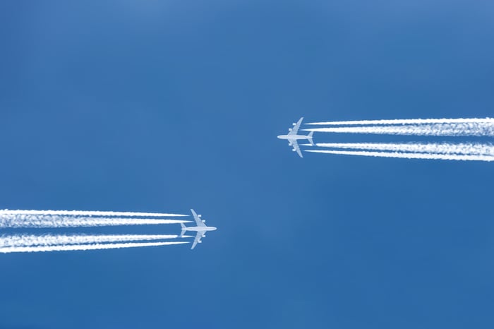 Two planes flying parallel, toward each other, with jet trails showing.