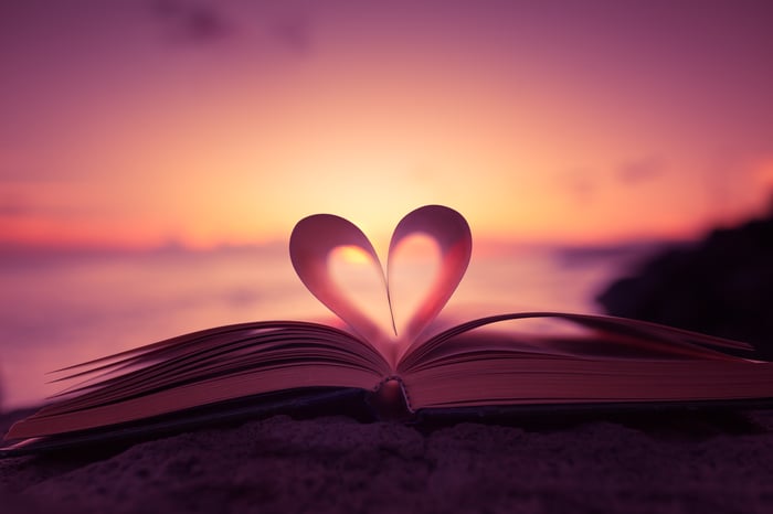 Book pages folded in to form a heart, with sunset in the background.