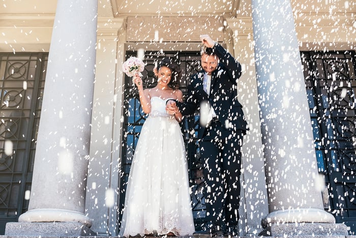 newly married couple holding hands and walking out of a church