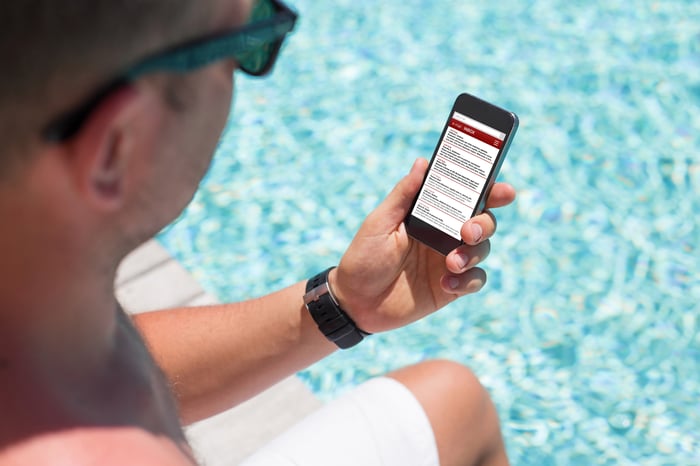 Man checking a mobile phone by a pool