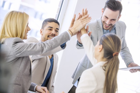 Group of professionally dressed men and women high fiving