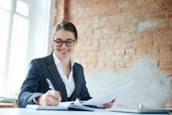 Smiling professional young female writing in a notebook