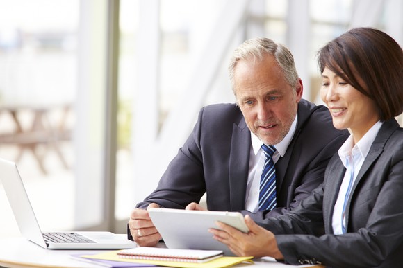 Older man in business suit reviewing document with woman in business suit