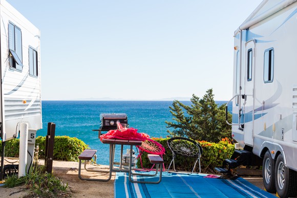 Two RVs parked at a camping site in Malibu, California, with the Pacific Ocean in background.