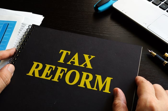 A person holding a binder with the words tax reform written on the cover. 