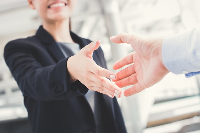 Professional female extending hand to shake with a man.