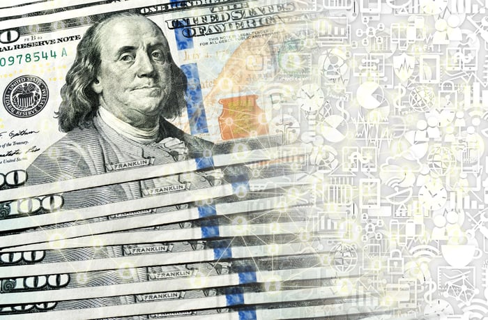 A fanned stack of hundred dollar bills transforming into digital money. 