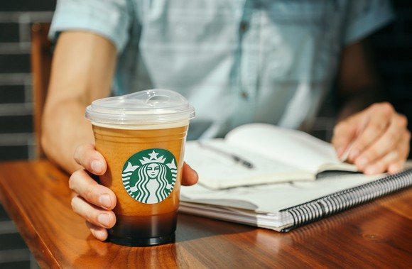 A person reading preparing to pick up a Starbucks coffee drink.