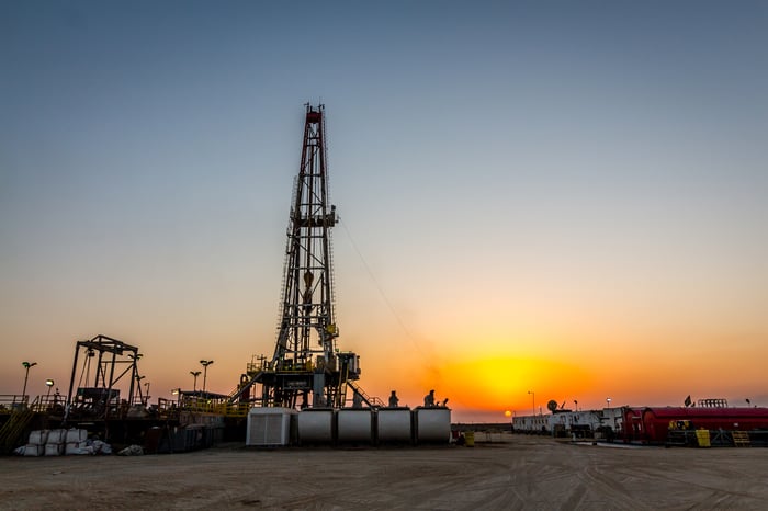 A drilling rig with the sun setting in the background