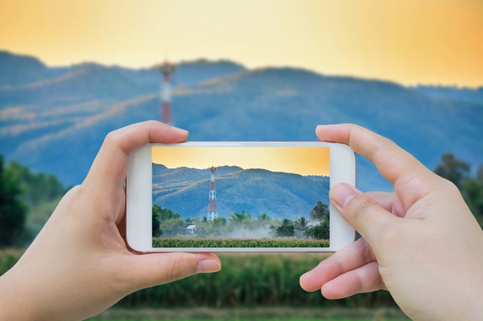 A person taking a picture of a cell tower with their mobile phone.