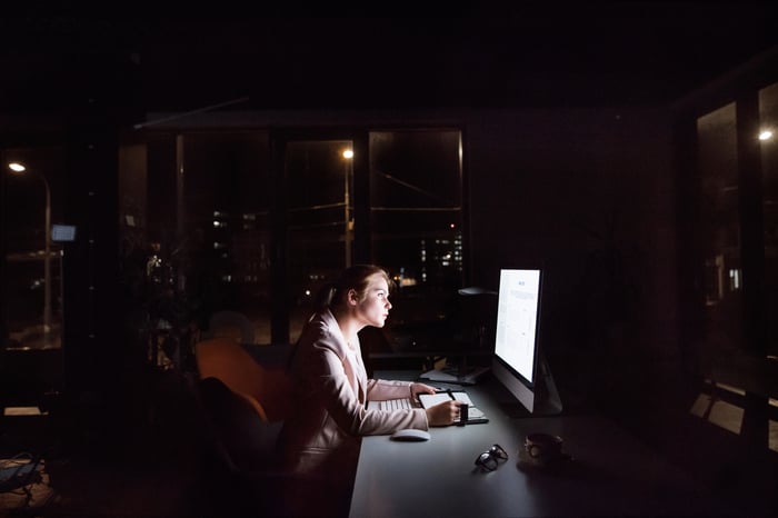 Woman sitting in front of a computer at night.