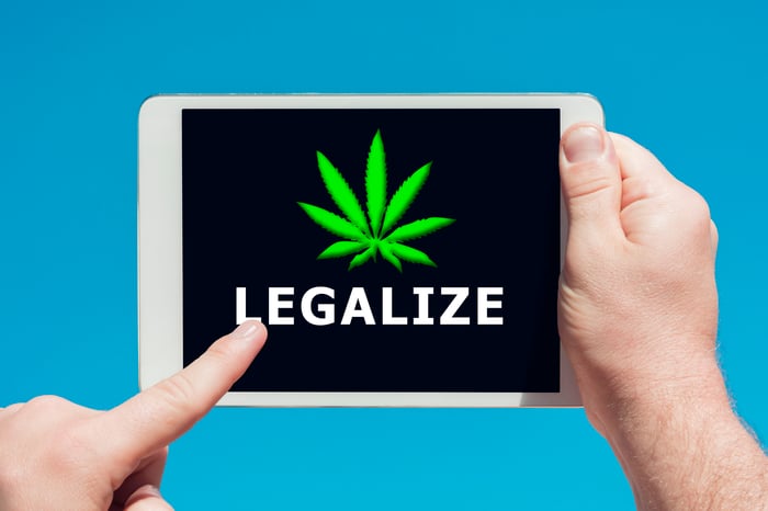 A person holding a tablet that shows a cannabis leaf with the word legalize underneath it. 