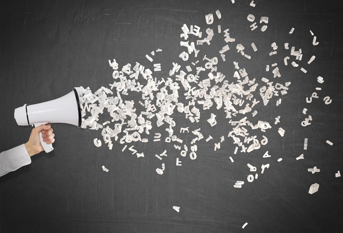 Letters shooting out of a megaphone being held in a person's hand.