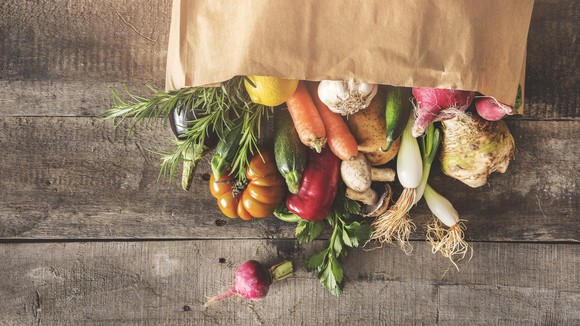 A bag of fresh vegetables spilling out on a table.