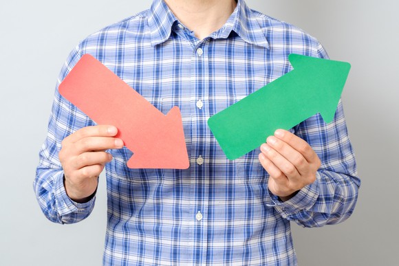 Man holding red arrow pointing down and green arrow pointing up