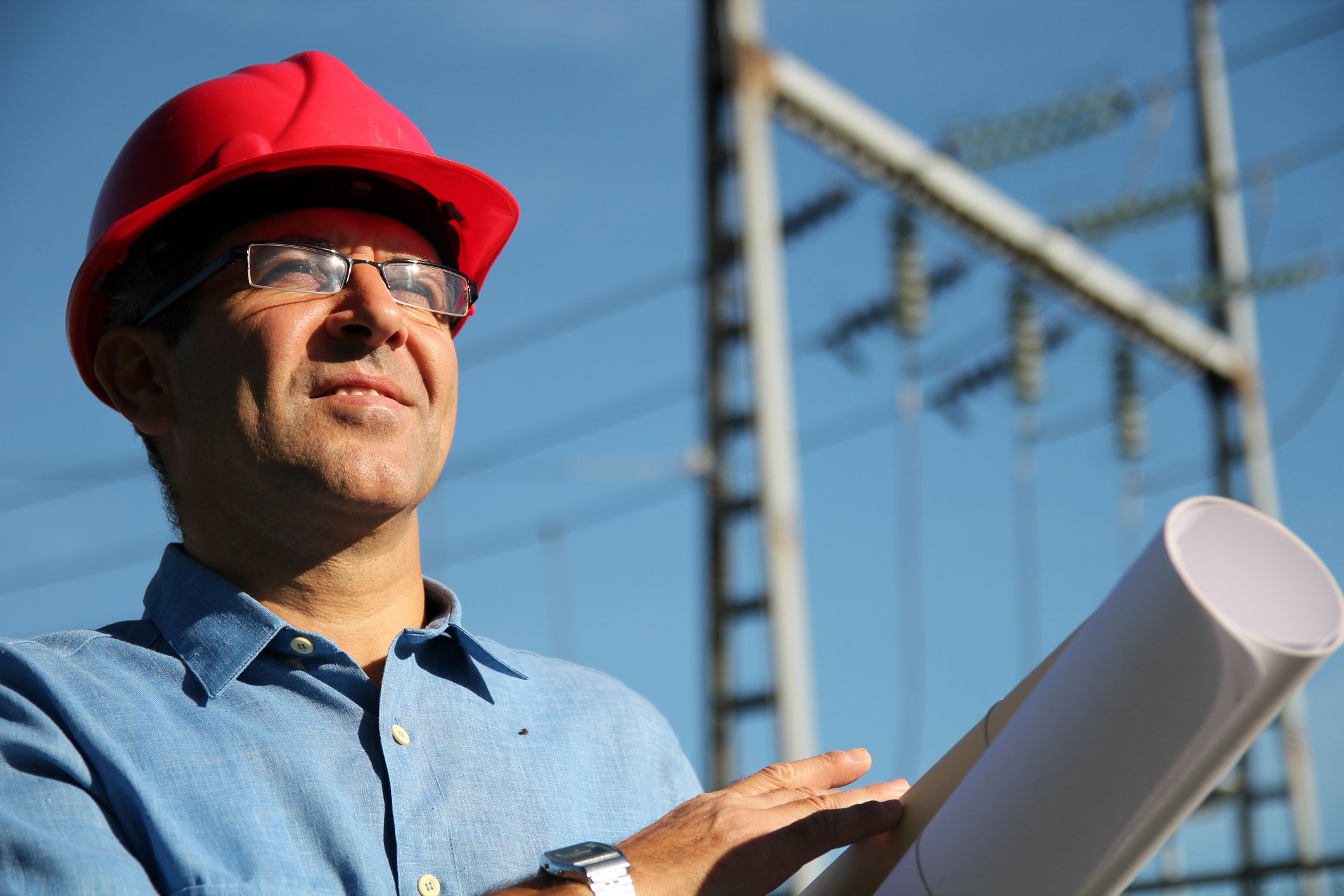18_09_20 A man with blueprints and high voltage power lines behind him_GettyImages-525436881