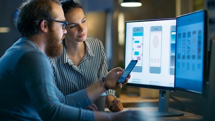 A man and woman working to design a smartphone app.