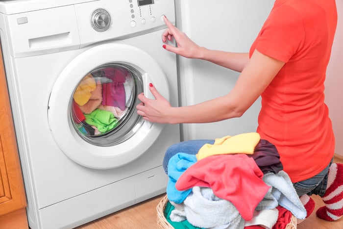 A woman unloading clean laundry from the dryer. 