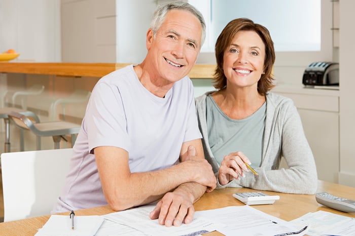 Smiling senior couple with documents and calculator.