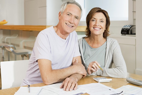 Smiling senior couple with documents and calculator.