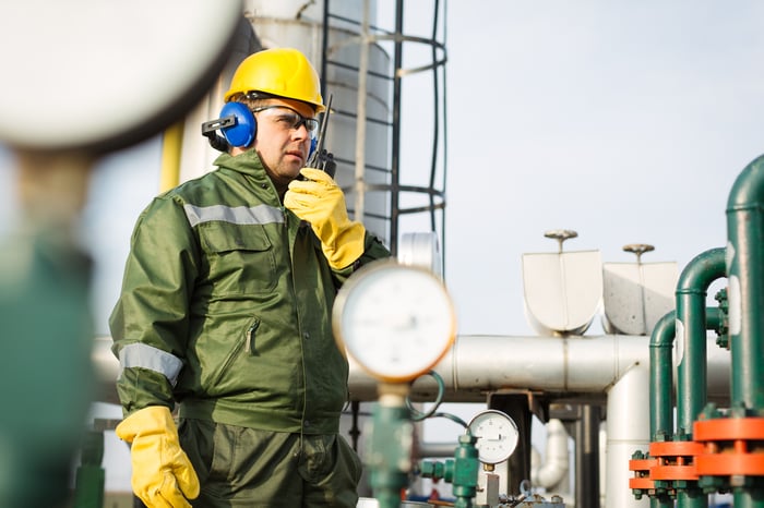 A man standing in front of midstream energy infrastructure equipment