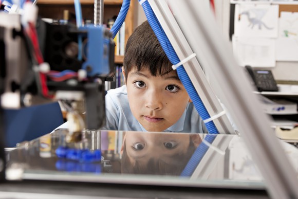 Child watching a 3D printer at work