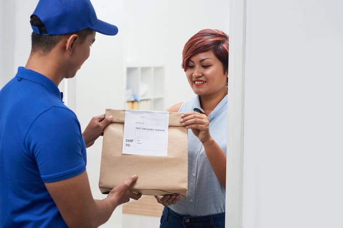 Delivery person handing over a food package to a customer.