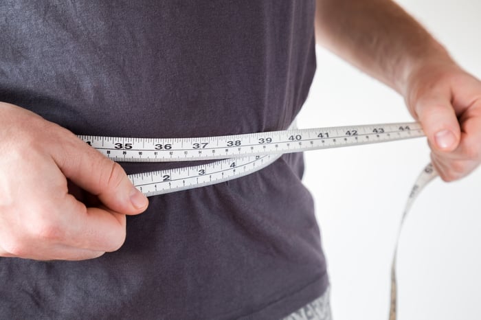 A measuring tape being held around a person's waist.