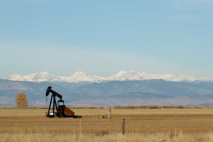 An oil pump in the field with mountains in the background.