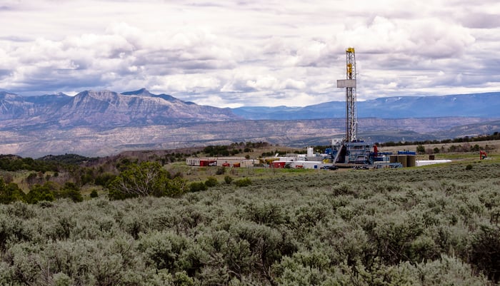 A drilling rig with mountains in the background.