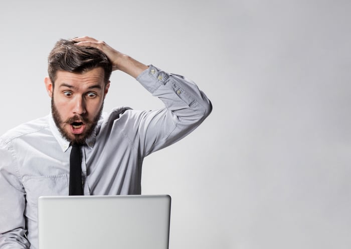 young man looking at laptop computer with expression of shock