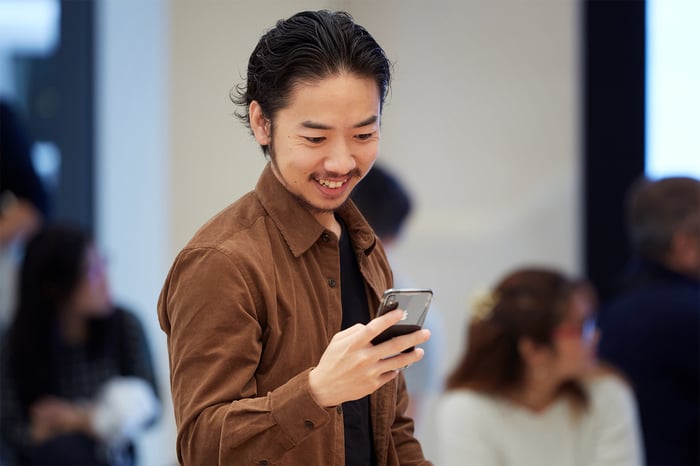 A man holding and looking at an iPhone XS in space gray.