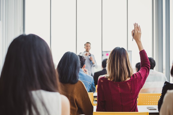 A woman raising her hand in class.