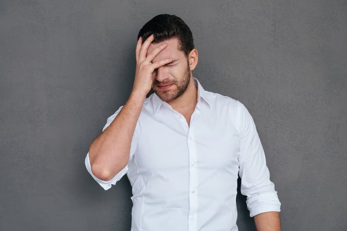 Man in a white shirt facepalming