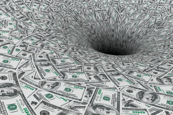 Hundred dollar bills in a whirlpool being sucked into a hole.