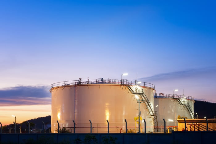 Petroleum storage tanks with the sun setting in the background.