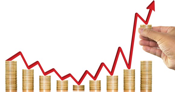 Man stacking coins progressively higher.