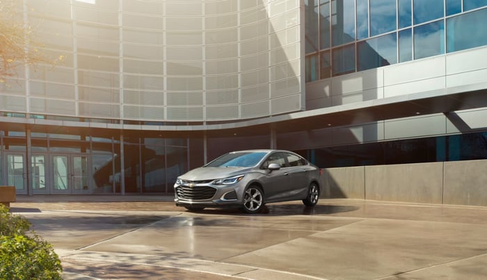 A gray Chevy Cruze parked in front of a building.