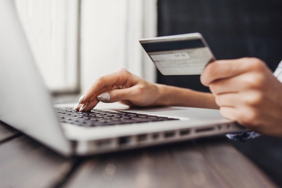 Woman typing on laptop while holding credit card