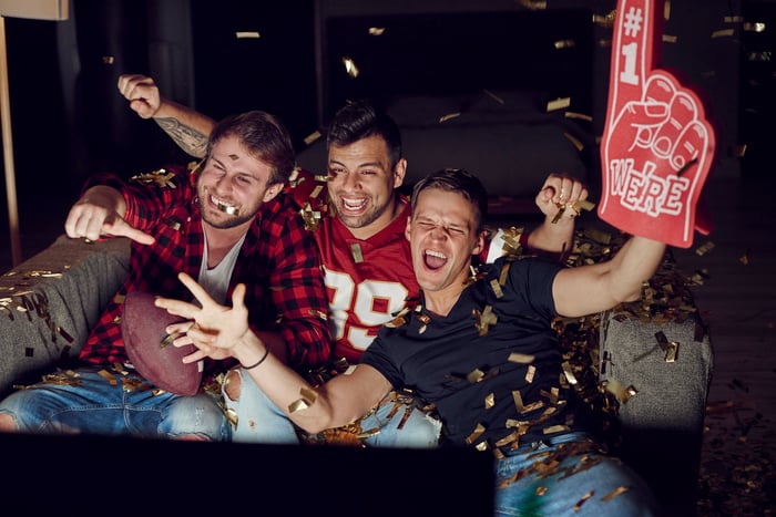 Three men watching a football game on television.