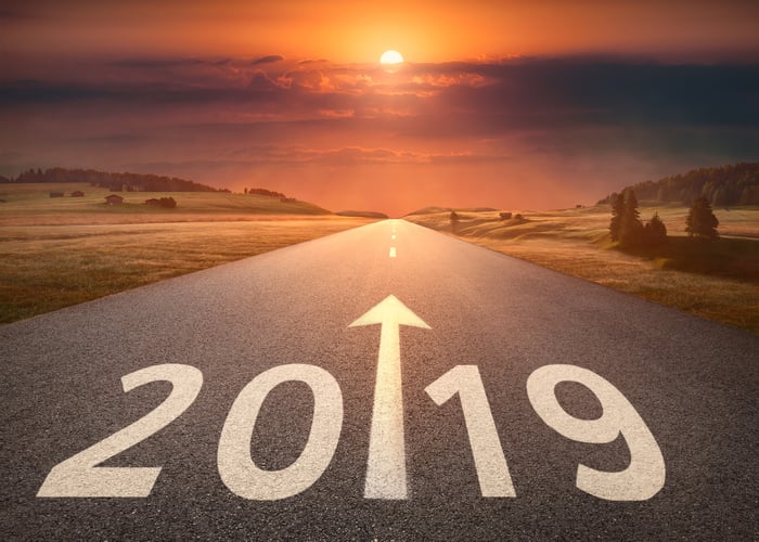 A road with 2019 and an arrow painted on it heading towards a beautiful horizon.