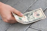 GETTY IMAGES Close-up of a hand picking up a lost ten dollar bill off the pavement