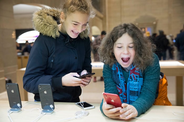 Two girls using iPhone XRs in an Apple store.