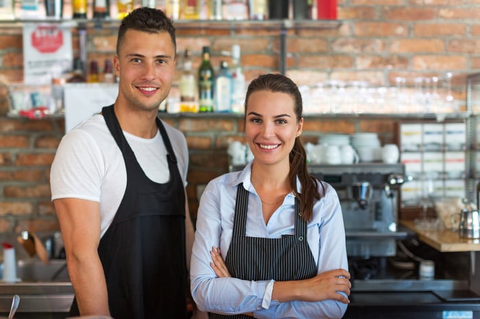 Smiling man and smiling woman in aprons