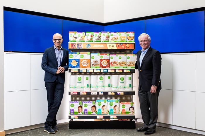 Microsoft CEO Satya Nadella and Kroger CEO Rodney McMullen pose in front of a shelf of Kroger Simple Truth products.