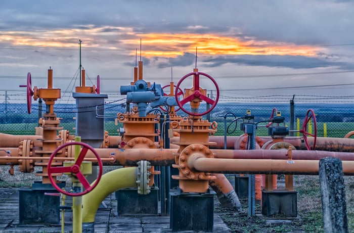 A natural gas field with pipeline valves and the sun setting in the background.