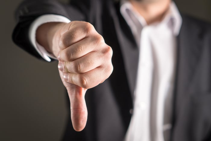 Man in suit giving a thumbs-down.