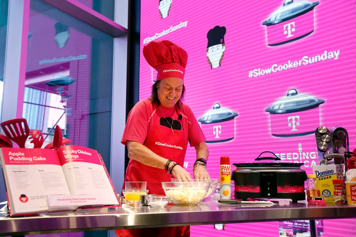 T-Mobile CEO John Legere in a chef's hat and apron cooking.