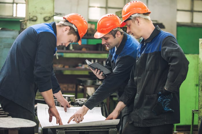 Three men looking over blueprints in an energy facility.