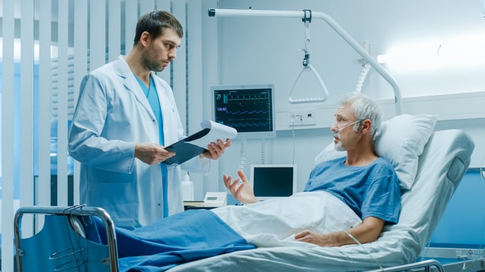 Man in hospital bed talking to doctor standing next to bed